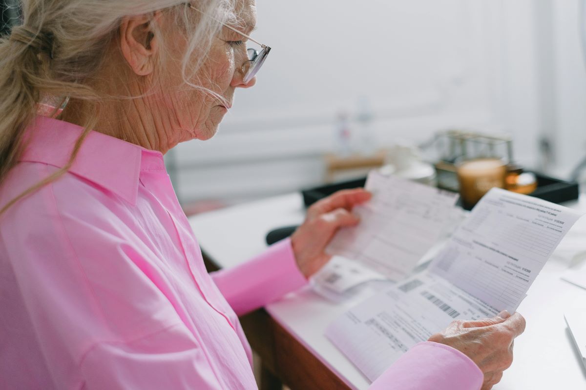 elder fraud senior woman reading her bills